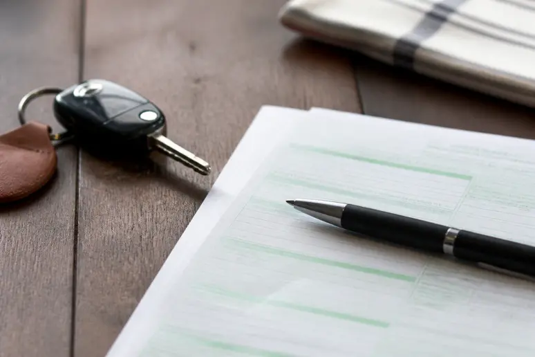 Document d'assurance pour voiture de collection posé sur une table avec une clé de voiture ancienne.
