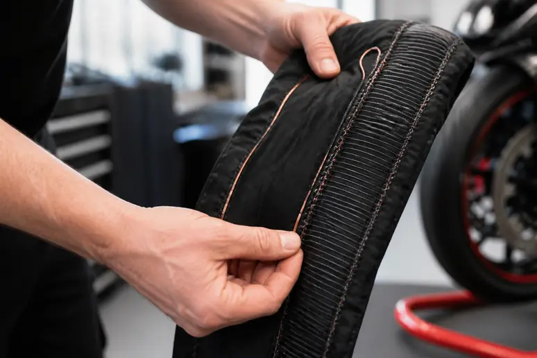 Mains de mécanicien examinant les fils en carbone et cuivre d'une couverture chauffante.
