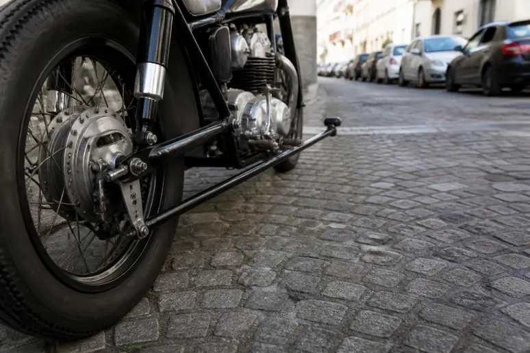 Gros plan sur l'arrière d'une moto ancienne, mettant en évidence la distance entre les roues.