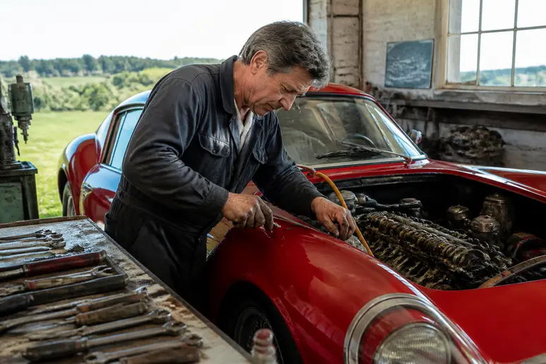Mécanicien expert travaillant sur le moteur d'une Ferrari 250 GTO dans un atelier.