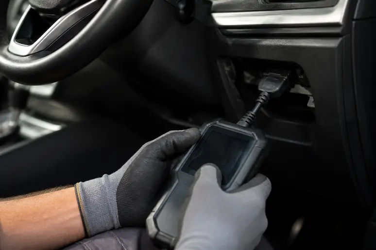 Un outil de diagnostic OBD pour interpréter un voyant Audi est utilisé par un mécanicien.