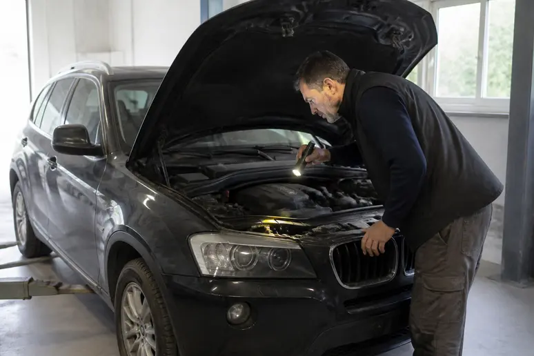 Un homme français vérifie le moteur d'un bmw crossover x3 d'occasion dans un garage.