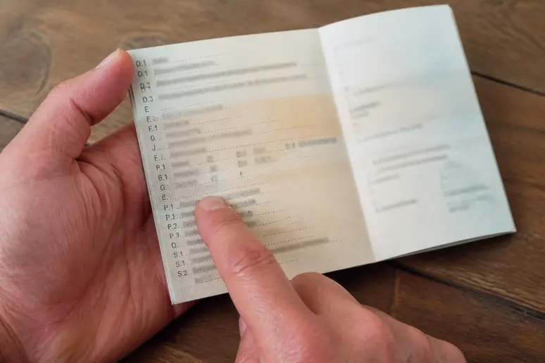 Main de conducteur montrant la case D.2 de la carte grise avec le code moteur.