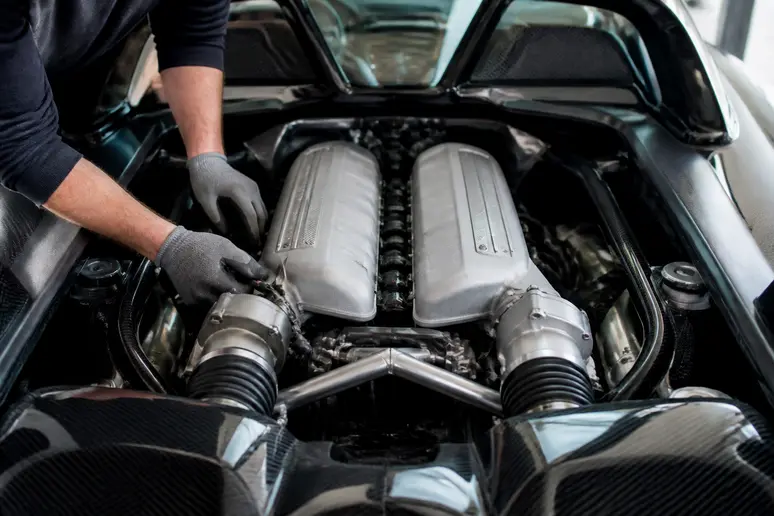 Gros plan sur le moteur V10 d'une porsche gt v10 dans un garage, un mécanicien travaille dessus.
