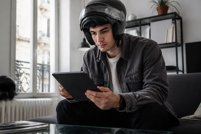 Jeune homme français comparant les assurances pour sa future R125 sur une tablette