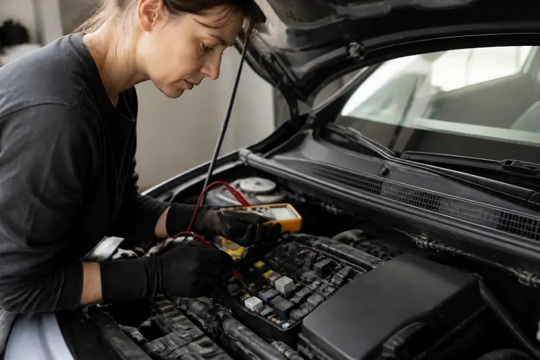 Diagnostic schéma sous capot Megane 3: femme avec multimètre vérifiant des connexions électriques.