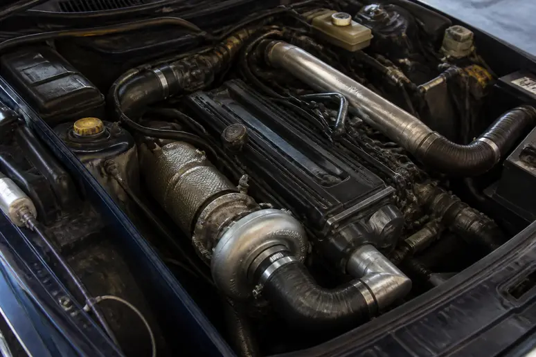Compartiment moteur d'une Saab 900 Turbo avec son turbocompresseur et sa tuyauterie d'origine.