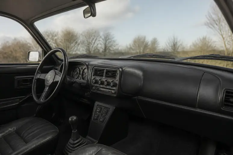 Tableau de bord vintage d'une Saab 900 classique avec son pare-brise incurvé et ses commandes.