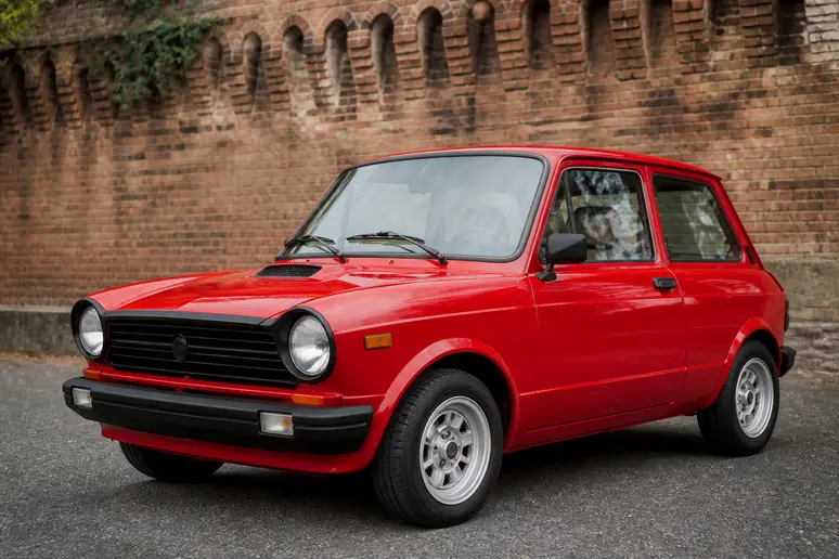 Autobianchi A112 Abarth rouge garée le long d'un mur en briques anciennes