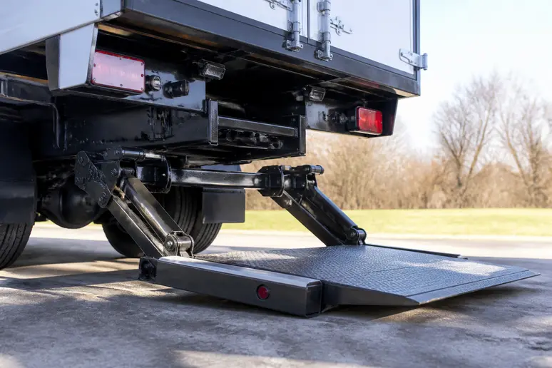 Bras hydrauliques et plateforme de hayon repliés sous le châssis d'un camion utilitaire