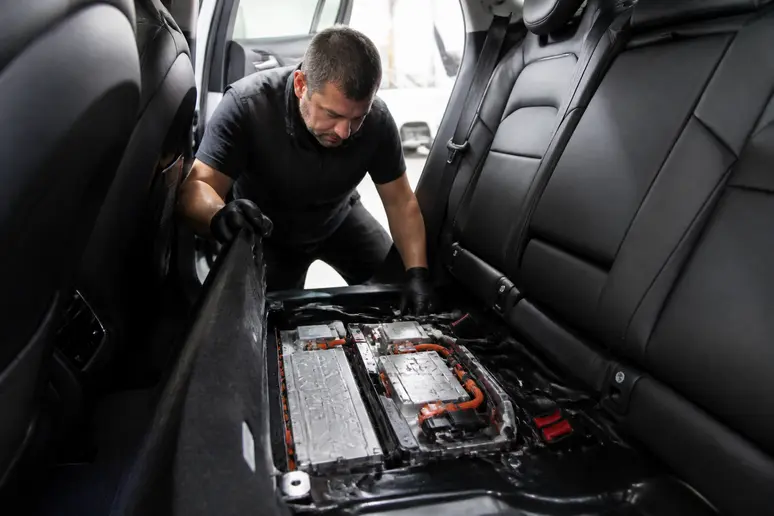 Mécanicien inspectant le pack batterie compact d'une architecture hybride sous le plancher.