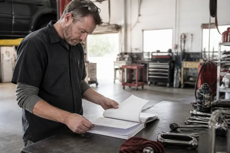 Un technicien consulte les bulletins de service technique sur son plan de travail en atelier.