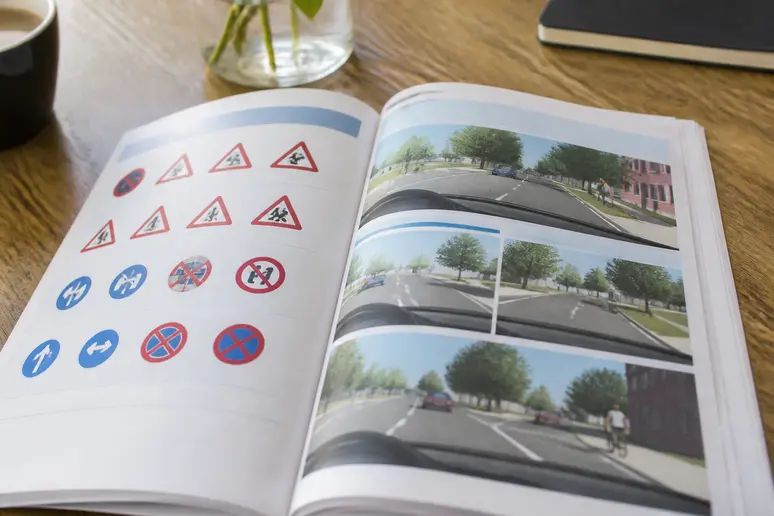 Manuel de préparation au code de la route ouvert sur une table en bois avec des illustrations de signalisation