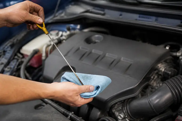 Mains d'un mécanicien vérifiant le niveau d'huile 5w30 pour quel moteur sur une voiture moderne