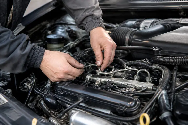 Mécanicien inspectant le compartiment moteur d'une voiture suite à un problème d'injection à contrôler