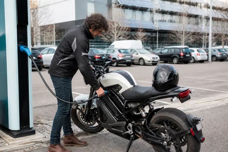Branchement du câble de recharge sur une moto 125 électrique à une borne publique.