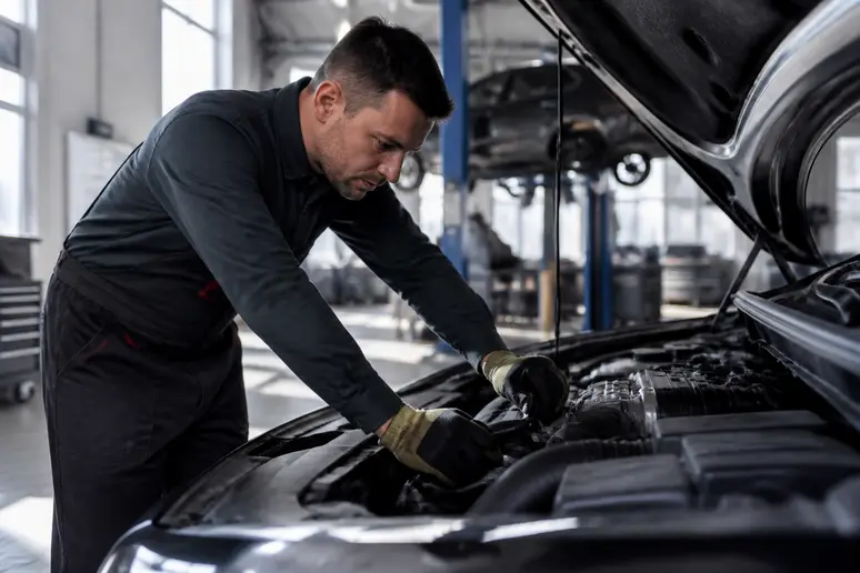 Mécanicien procédant à une vérification technique sous le capot d'une voiture en atelier